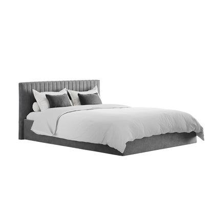 The Dublin Silver Upholstered 4ft6 Double Ottoman Bed features a ribbed headboard, white bedding, and white and gray accent pillows for a sleek, modern look in any space.